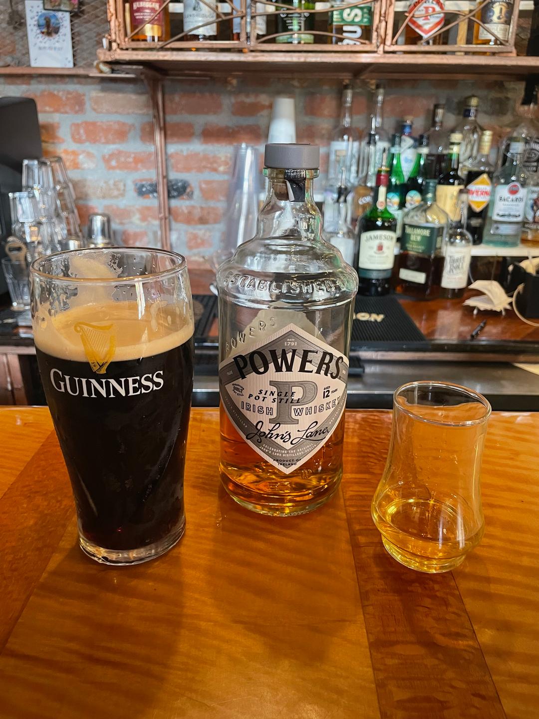 A glass of Guiness, Powers Whisky Bottle and glass of Whisky