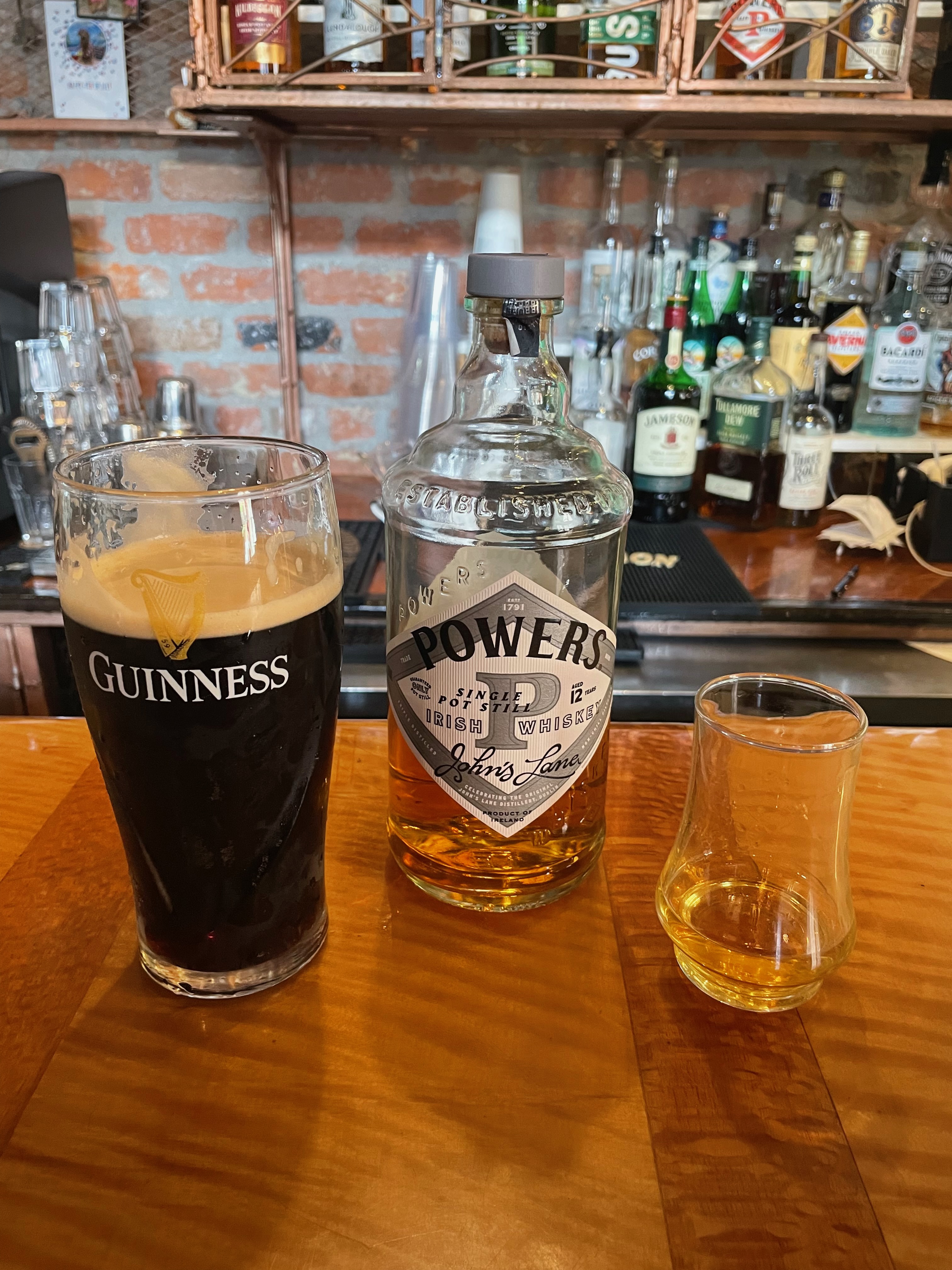 A glass of Guiness, Powers Whisky Bottle and glass of Whisky